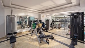 A gym with weightlifting equipment, mirrors, and a polished floor. - Miami Beach Hotel & Apartment (Da Nang)