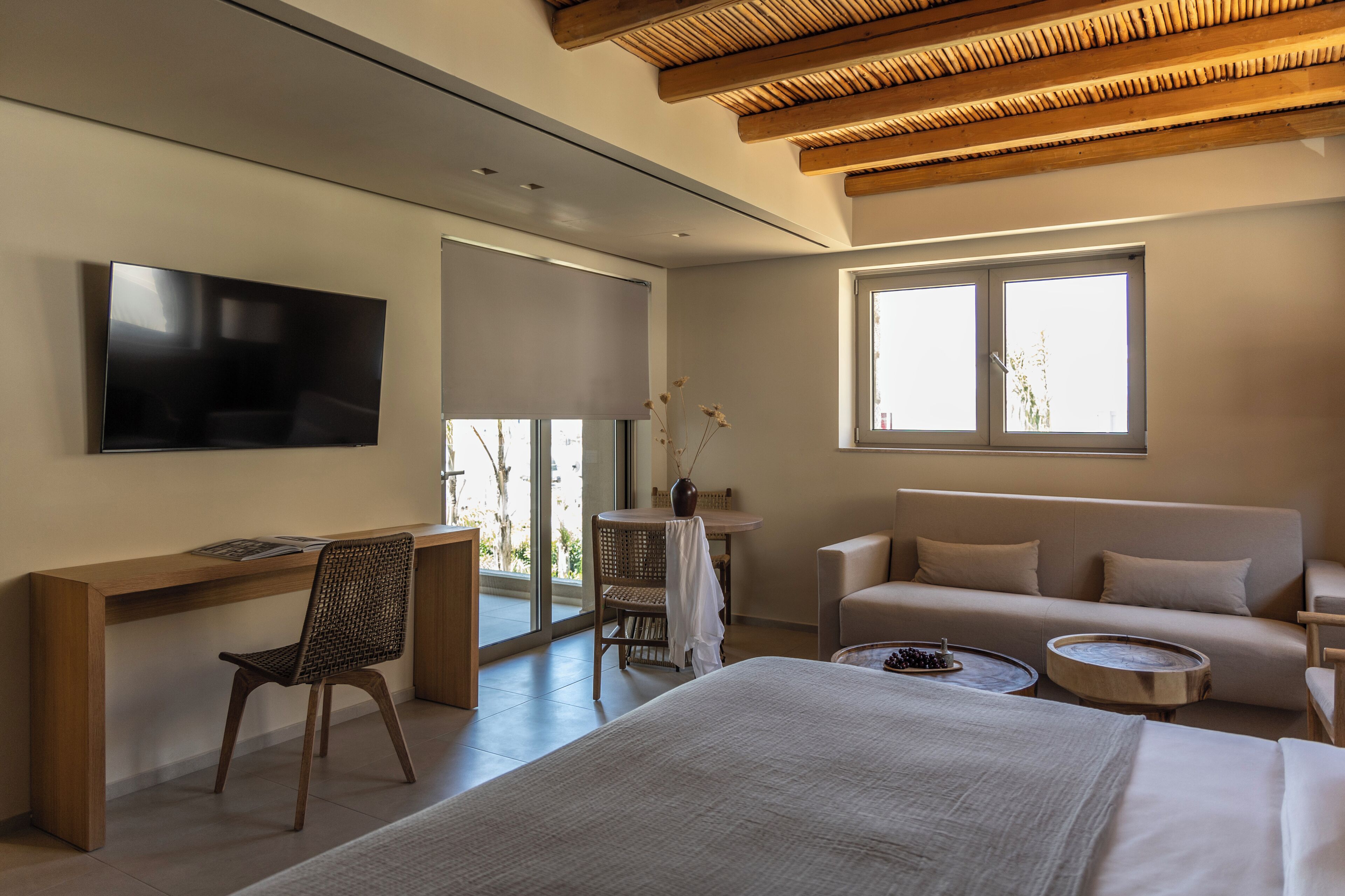 Una habitación de hotel moderna con una cama, un escritorio, un televisor, un sofá y una ventana.