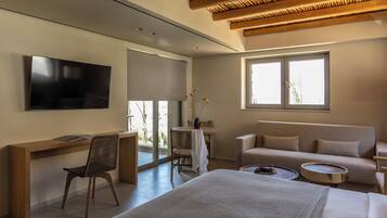 Una habitación de hotel moderna con una cama, un escritorio, un televisor, un sofá y una ventana.