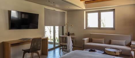 Una habitación de hotel moderna con una cama, un escritorio, un televisor, un sofá y una ventana.
