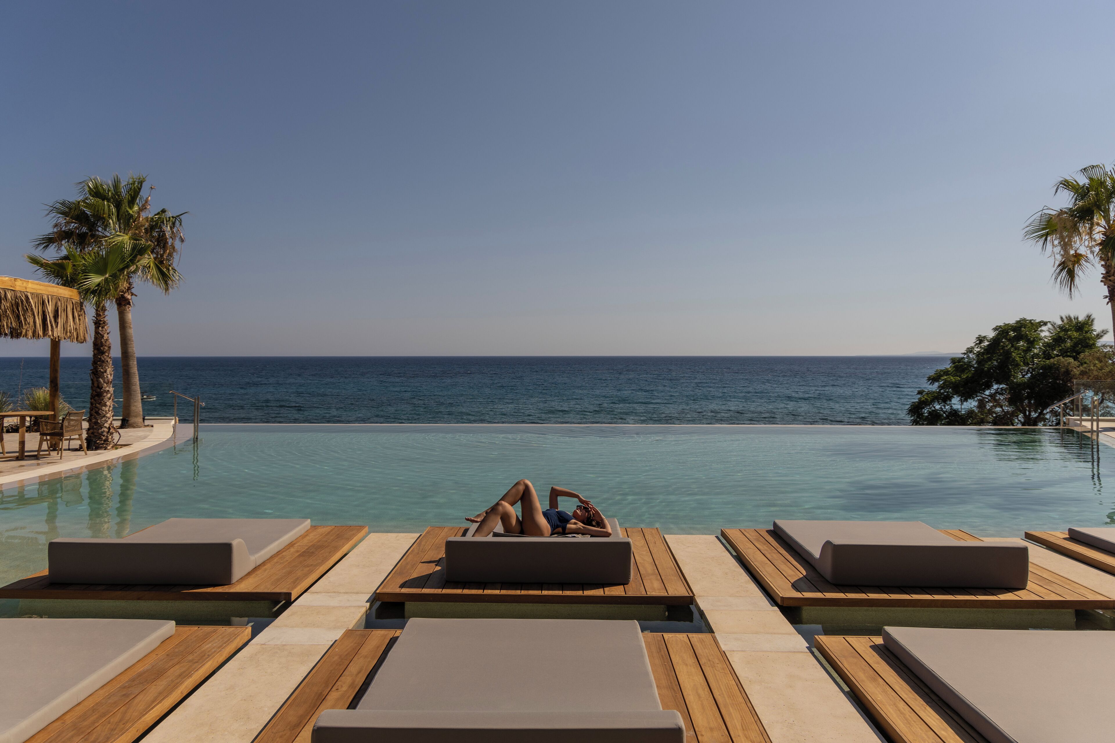 Un espace aménagé au bord de la piscine, avec des chaises longues et une vue sur l’océan.