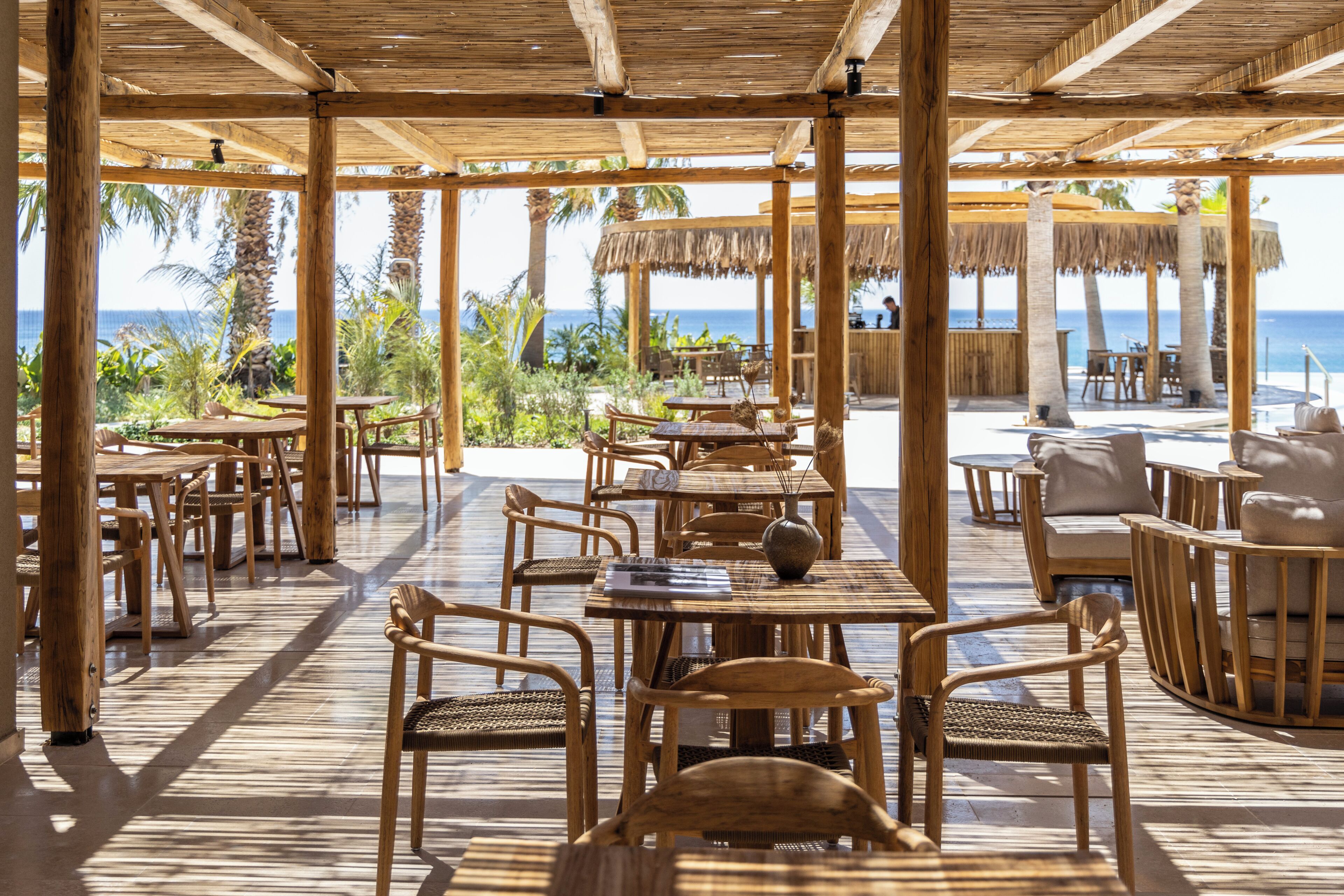 An outdoor seating area with wooden furniture and a view of the ocean.