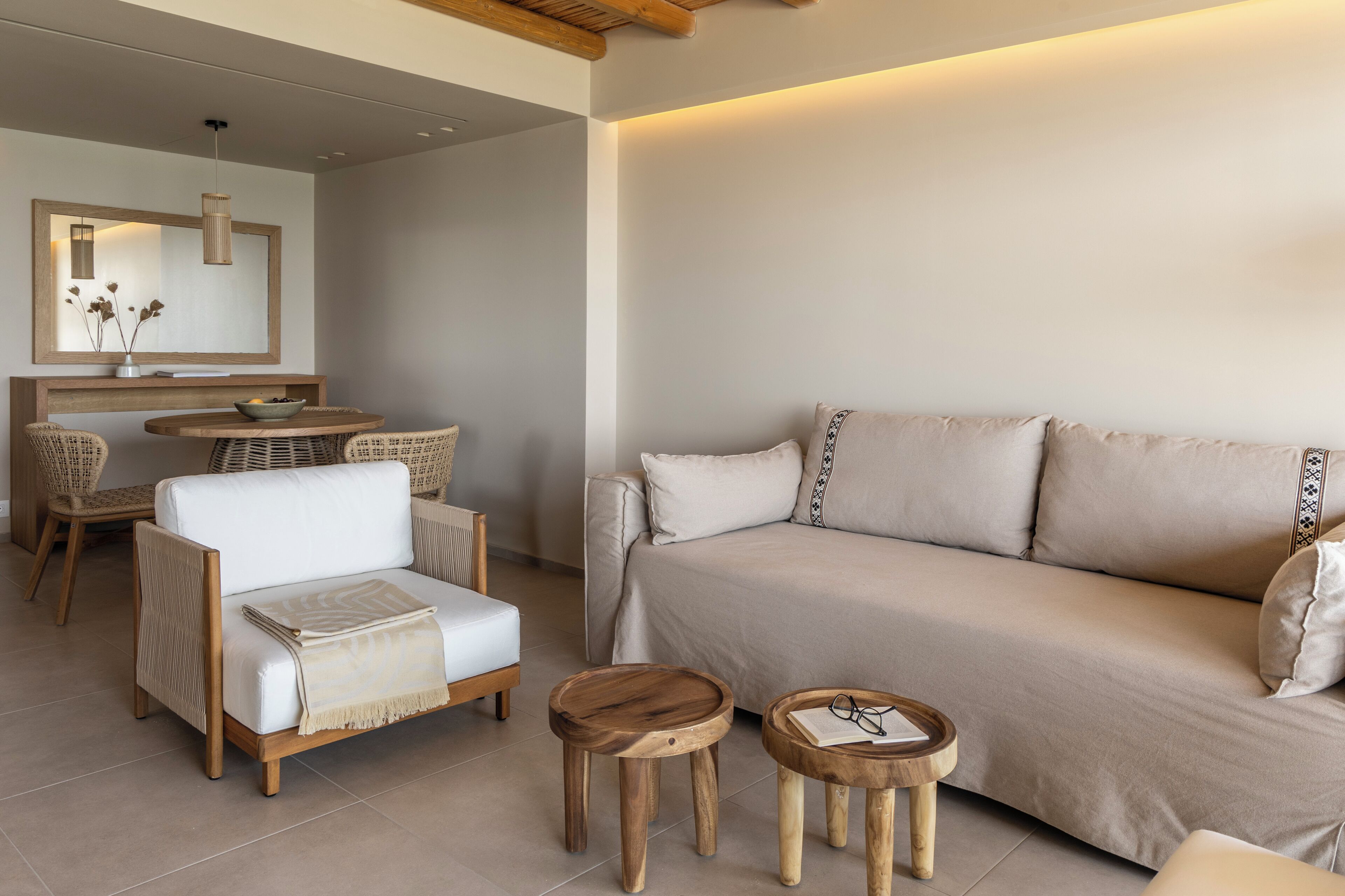 Een moderne woonkamer met een bank, twee stoelen, een klein houten tafeltje en een eethoek met tafel en stoelen.