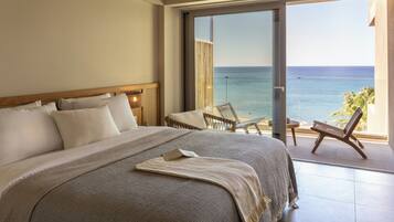 Un dormitorio con una cama grande, vista al mar y un balcón con sillas.