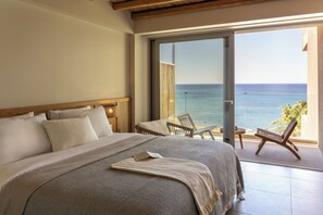 Un dormitorio con una cama grande, vista al mar y un balcón con sillas.