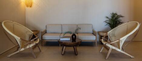 A modern living room with a sofa, two wicker chairs, a coffee table, and a hanging light fixture.