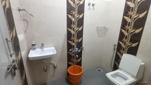 Et lille badeværelse med en hvid vask, toilet og brusebad.