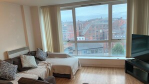 Una sala de estar moderna con un ventanal grande, un televisor de pantalla plana y un conjunto de sofás.