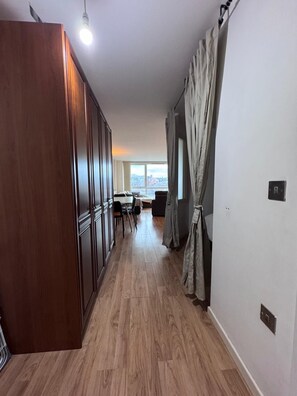 Ein Flur mit Holzboden, ein Essbereich mit Stühlen und einem Tisch sowie ein Blick durch ein Fenster.