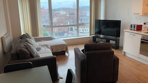 Una sala de estar moderna con un sofá, un televisor y una zona de cocina con un tostador.