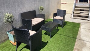 A patio with wicker furniture, a glass table, and small potted plants. - Cosy house - walking distance to beach and market (Dives-sur-Mer)