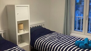 A room with two beds, a wardrobe, a lamp, and a window with curtains. - Cosy house - walking distance to beach and market (Dives-sur-Mer)