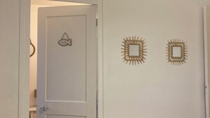 A room with a white door, a fish-shaped decoration, and two square mirror-like wall decorations. - Cosy house - walking distance to beach and market (Dives-sur-Mer)