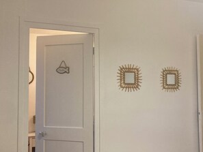 Ein Zimmer mit einer weißen Tür, einer fischförmigen Dekoration und zwei rechteckigen Wandzierden.