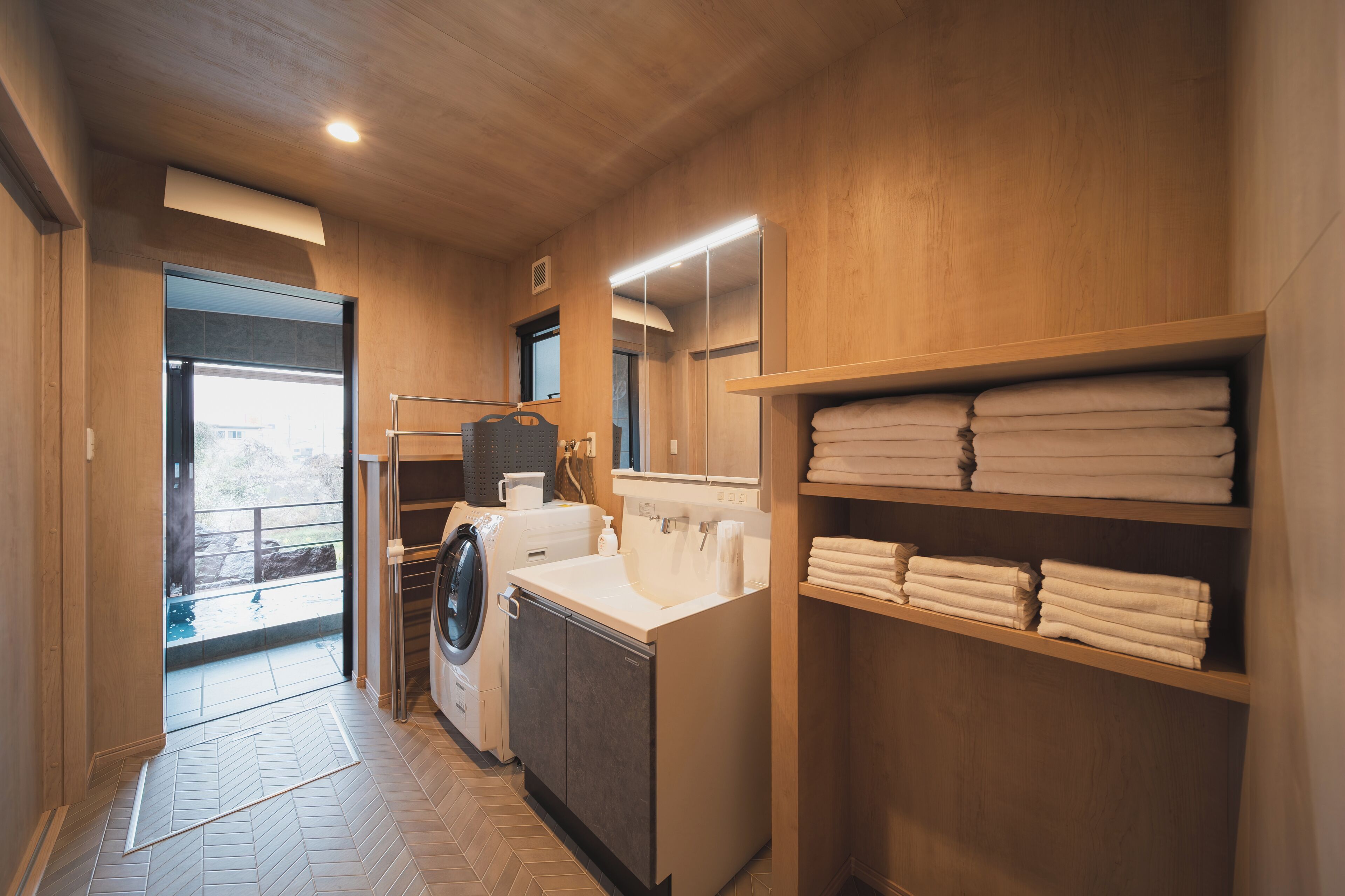 A laundry room with a washing machine, dryer, and shelves with folded towels.