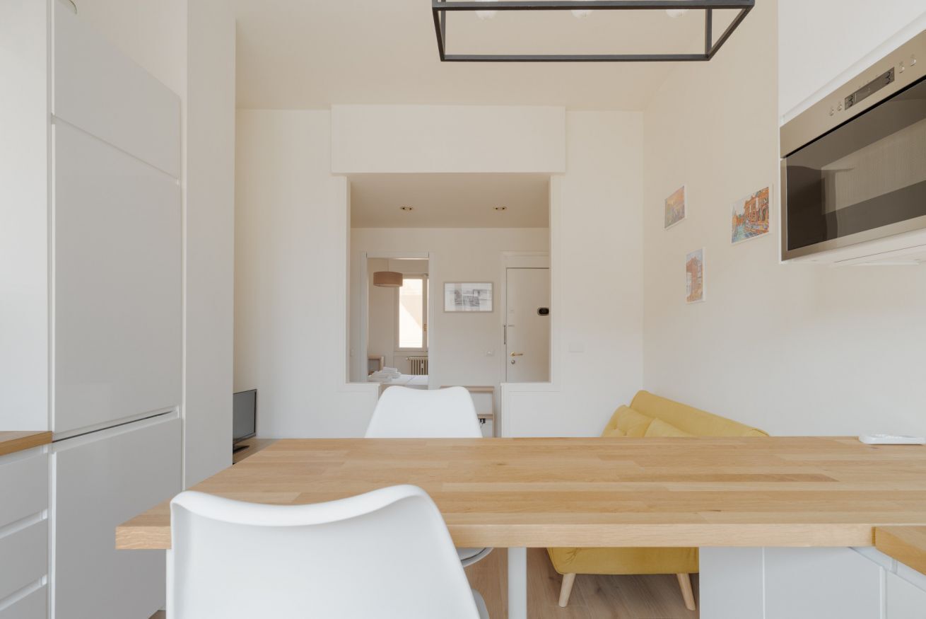 Eine moderne Küche mit weißen Schränken, einer Holz Arbeitsplatte und einem gelben Stuhl.