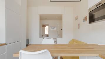 Eine moderne Küche mit weißen Schränken, einer Holz Arbeitsplatte und einem gelben Stuhl.