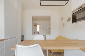 Eine moderne Küche mit weißen Schränken, einer Holz Arbeitsplatte und einem gelben Stuhl.