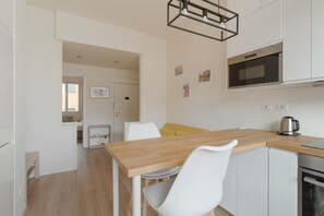 Eine moderne Küche mit weißen Schränken, einer Holzarbeitsplatte, einem eingebauten Backofen und einer Pendelleuchte.