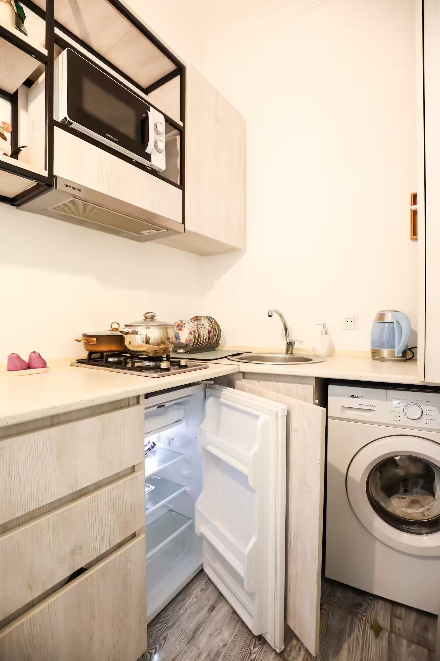 Une cuisine compacte équipée d’un four à micro-ondes, d’une cuisinière, d’un évier et d’un lave-linge encastré.
