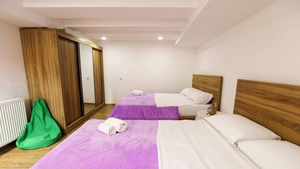 Une chambre d’hôtel avec deux lits, un miroir, un radiateur et un fauteuil en forme de haricot vert.
