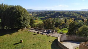 A terrace with outdoor seating, surrounded by a lush green landscape and distant hills. - 100% Authentic Tuscany: A Great Villa in the Countryside for Families and Groups (Toscana)