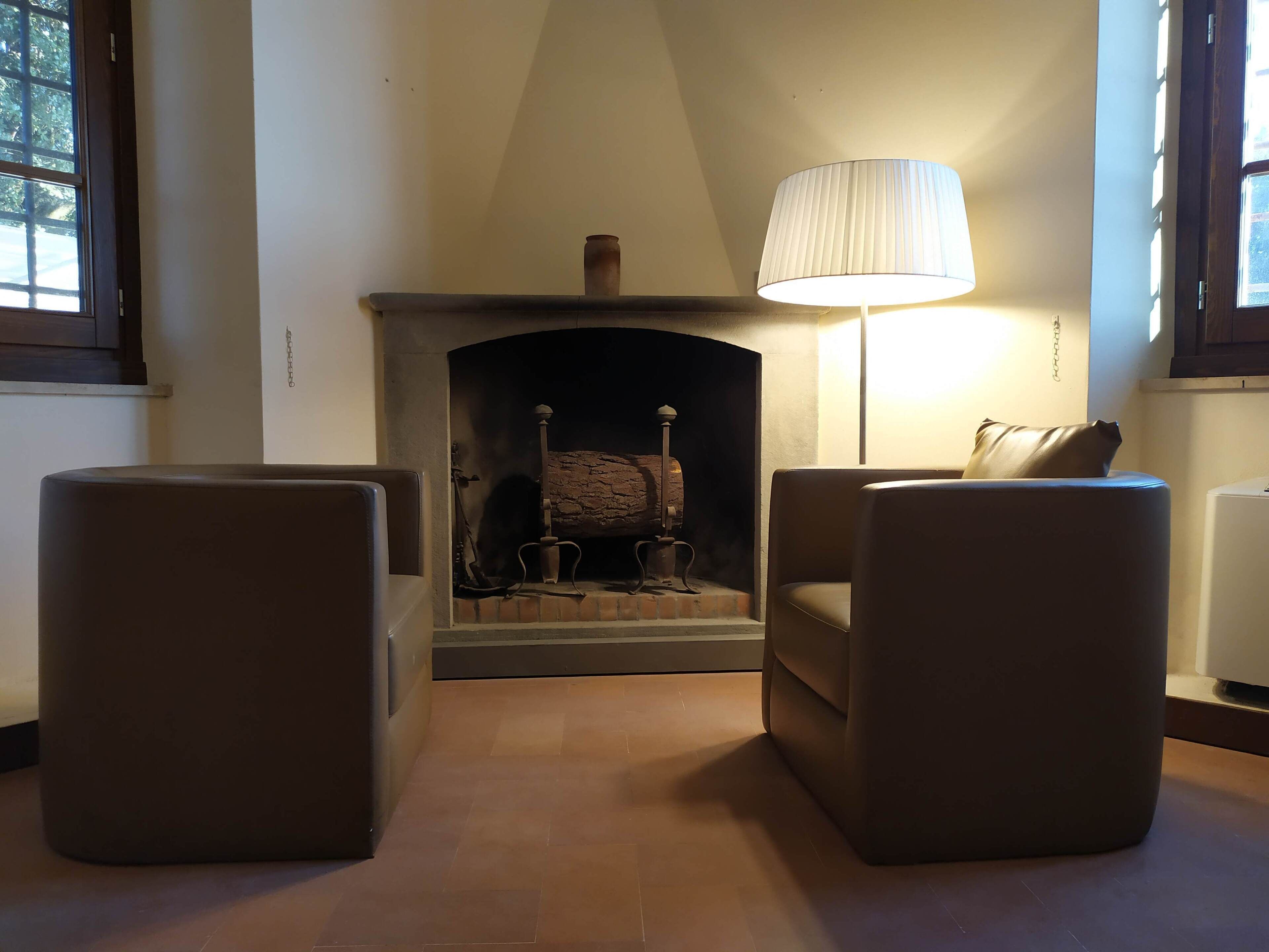 A living room with a fireplace, two armchairs, and a lamp.