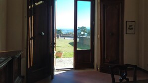 A room with a large arched window, a door, and a chair. - 100% Authentic Tuscany: A Great Villa in the Countryside for Families and Groups (Toscana)
