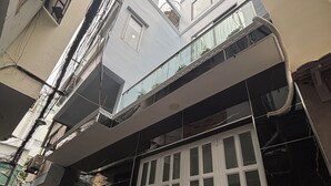 Um edifício com vários andares, varanda, portão e fiação elétrica aparente.