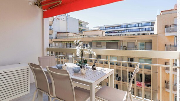 A balcony with a table, chairs, and a red awning. - Quartier Carlton 3 rooms South with terrace (Cannes)