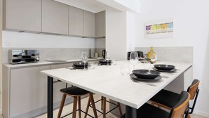 A modern kitchen with a central island, built-in appliances, and a dining area with chairs and a table. - Quartier Carlton 3 rooms South with terrace (Cannes)