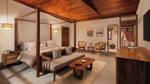 A room with a four-poster bed, a sofa, a wooden coffee table, and a dining table. There are chairs around the dining table and a small side table with a lamp. - Samsara Hill Resort By Leisure Hotels (Mussoorie,)