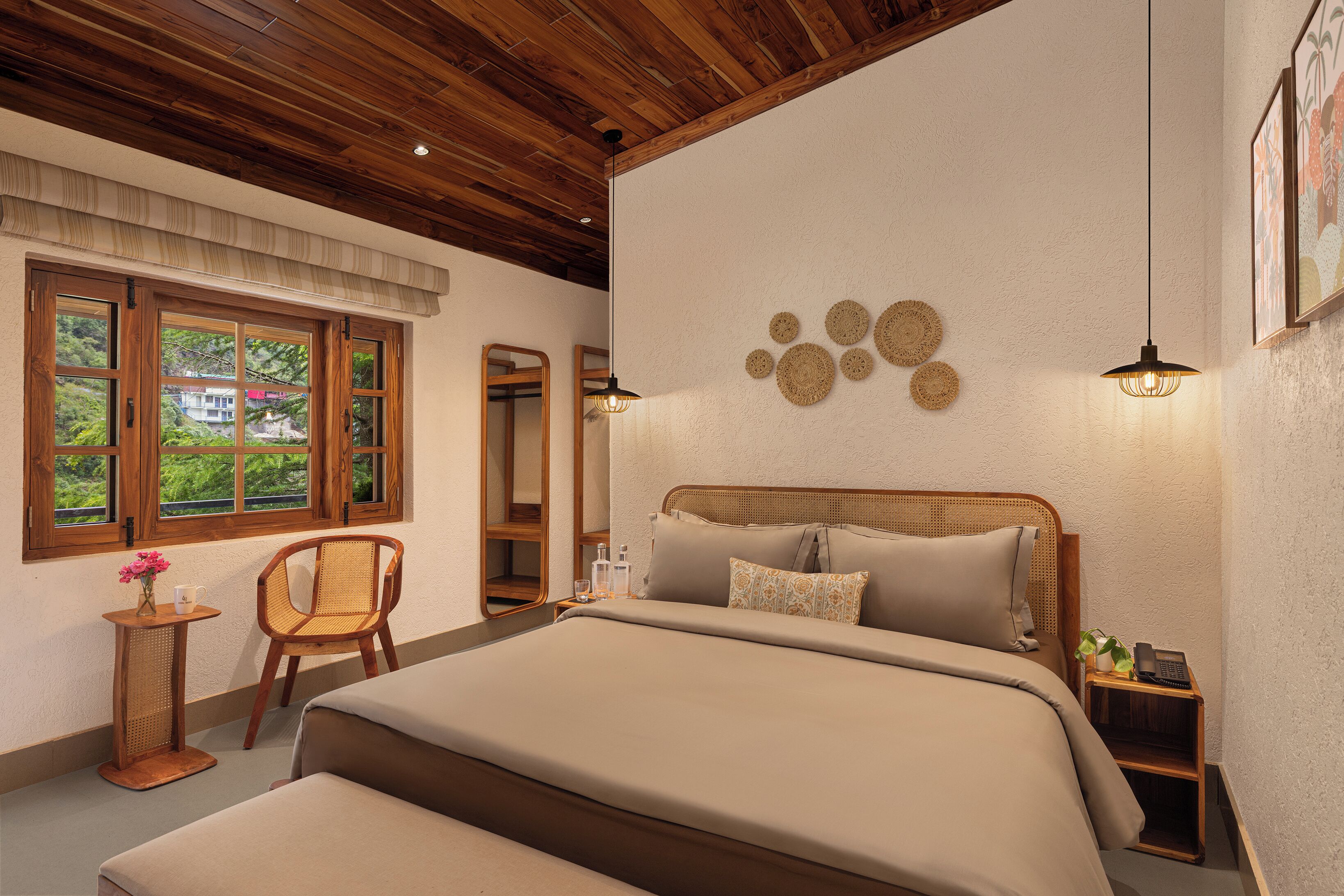 Une chambre avec un plafond en bois, un lit avec une tête de lit, une table de chevet, une chaise, une fenêtre donnant sur un beau paysage et des éléments de décoration murale.