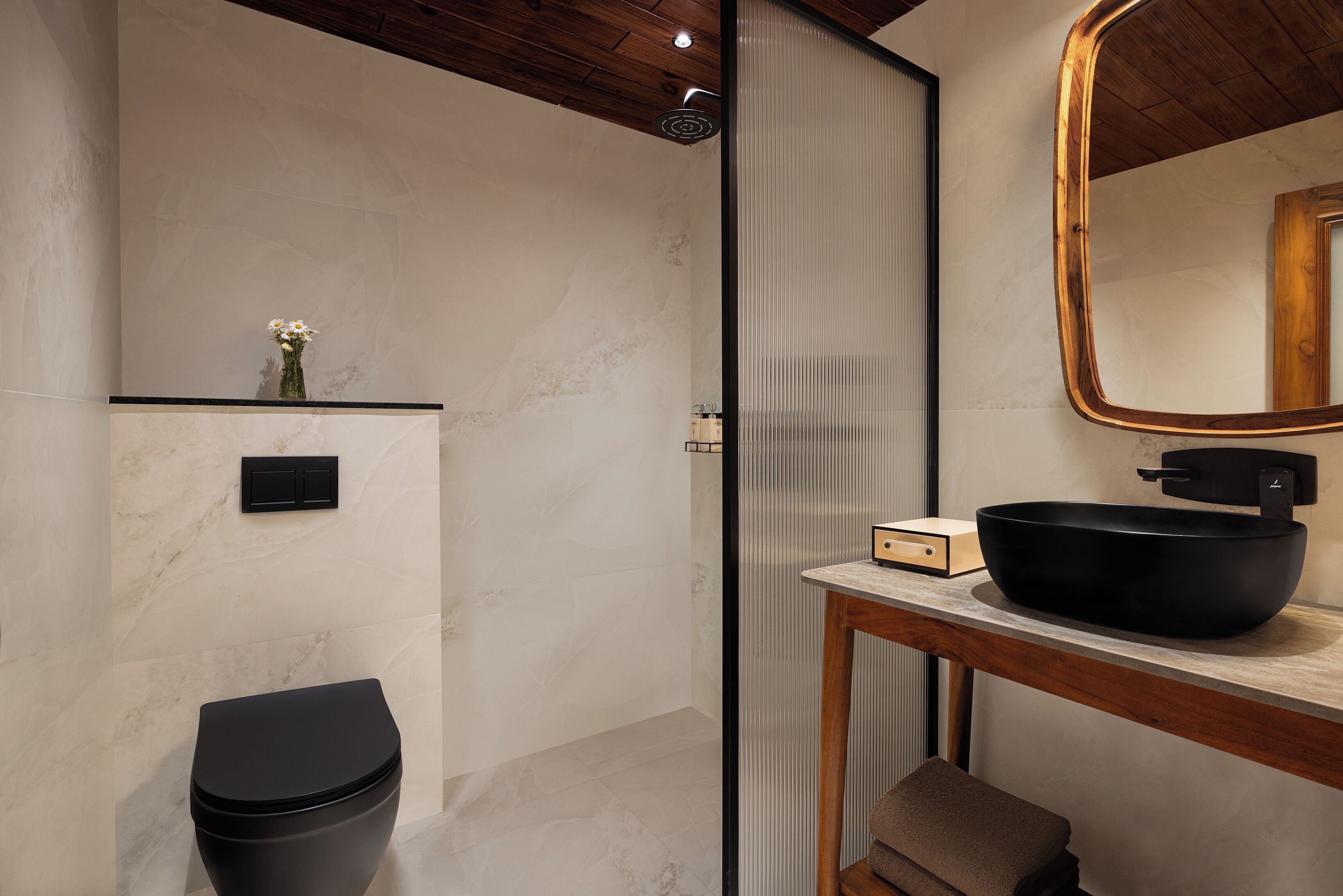 Une salle de bain moderne avec des toilettes noires, un mur en marbre, un meuble-lavabo en bois et un grand miroir.