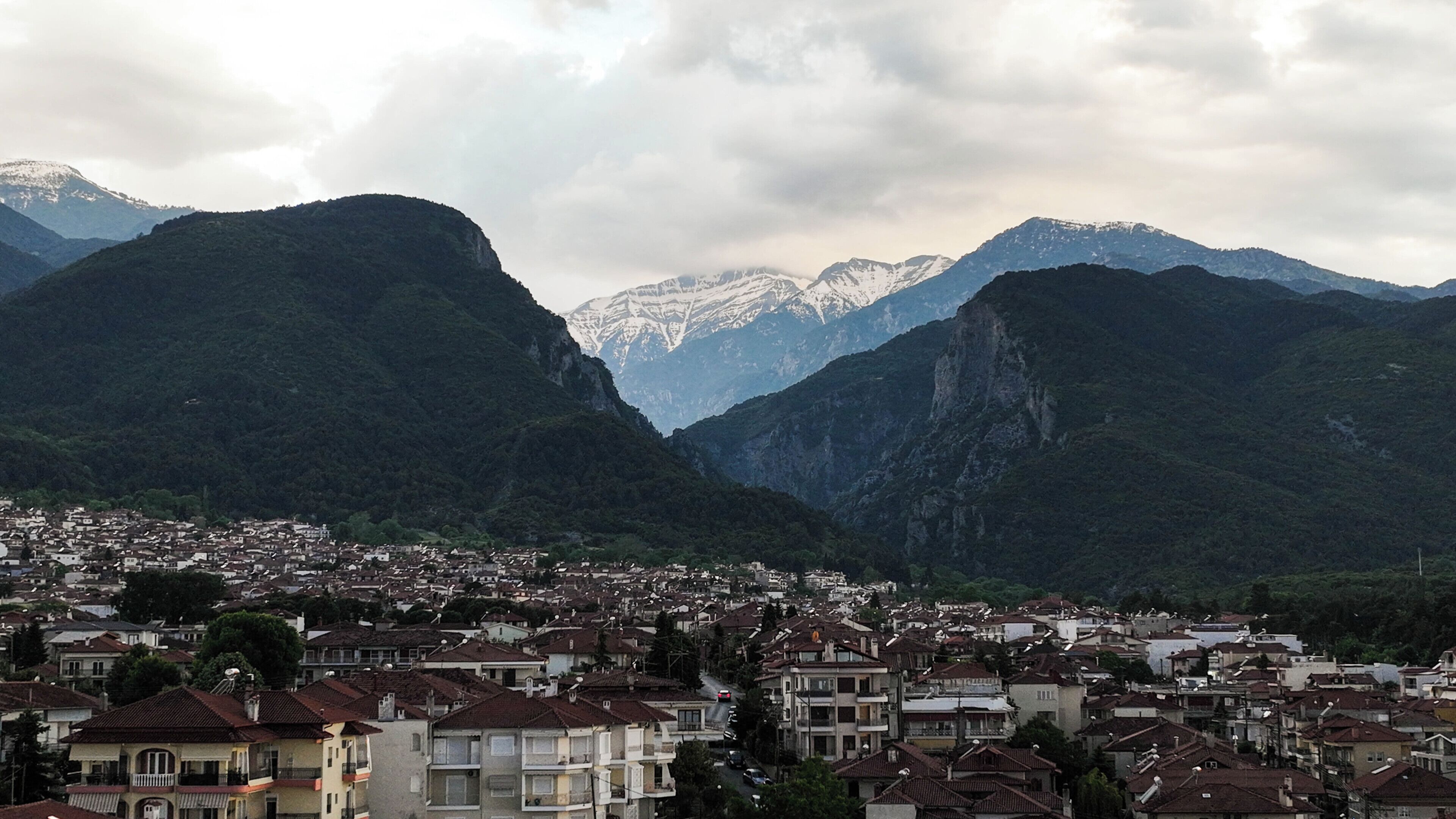Un pueblo situado entre montañas, con vistas a picos nevados en la distancia.