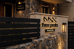 Un muro de piedra con un letrero que dice 'Three Peaks Elevated Stay' y bancos de madera.