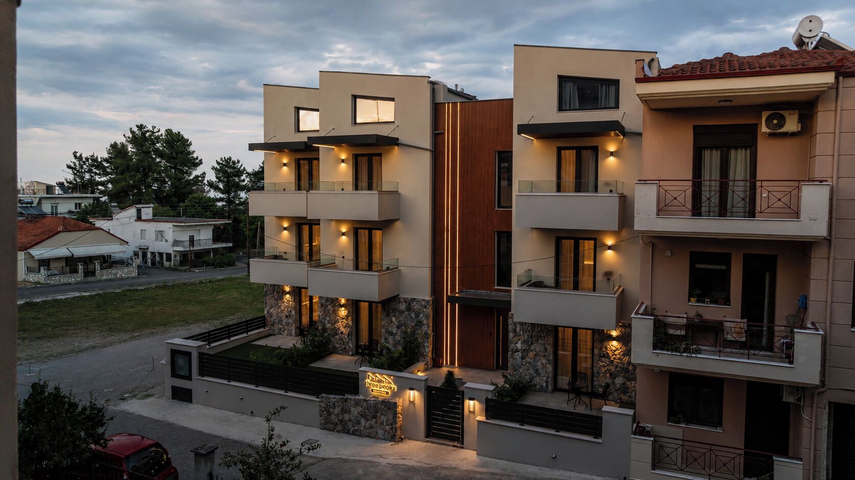 A modern multi-story residential building with balconies, a stone facade, and a well-lit entrance.