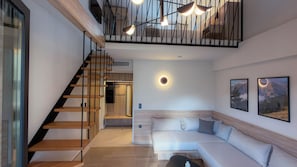 A modern interior with a wooden staircase, a sofa, and framed pictures on the wall. - Threepeaks Elevated Stay (Litochoro)
