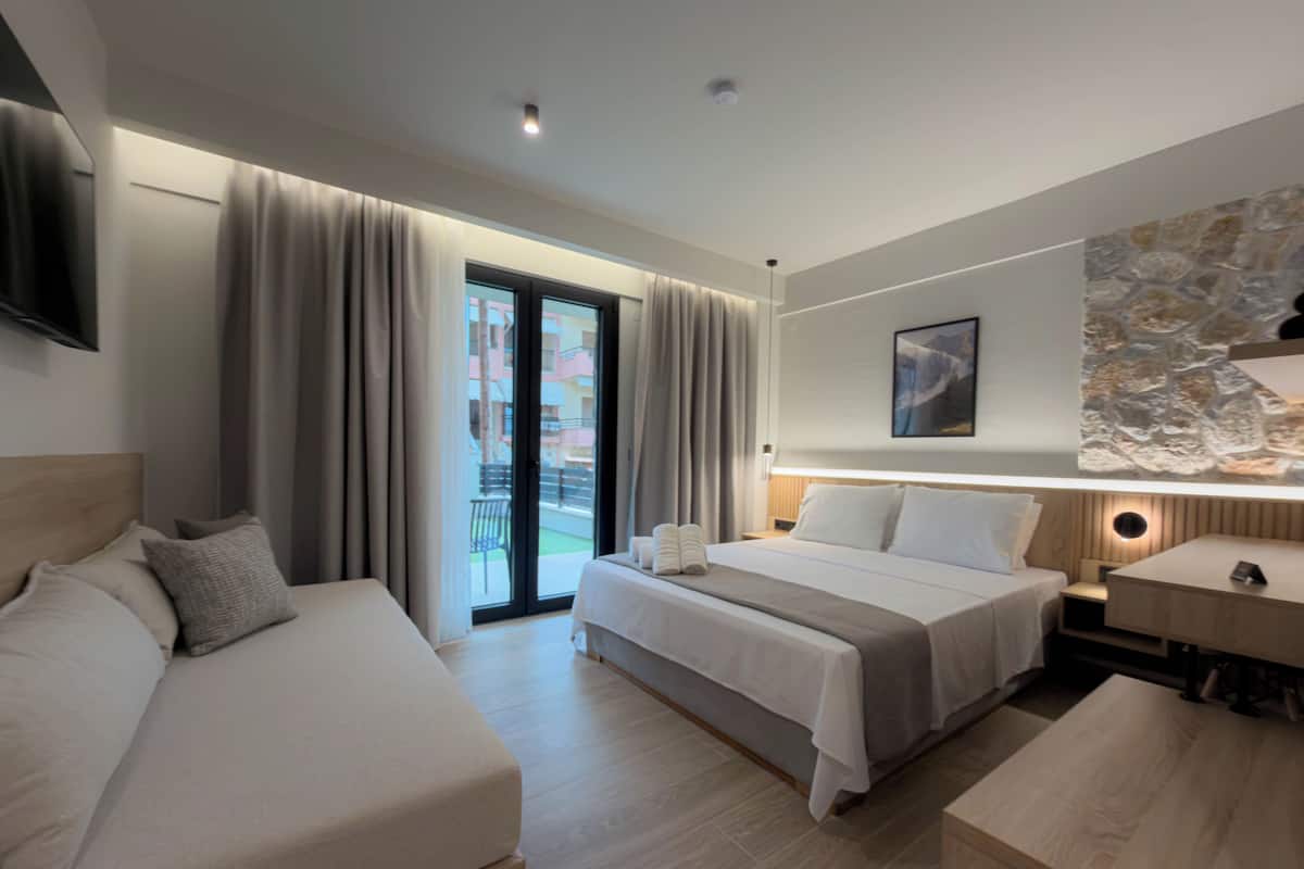 A hotel room with a bed, a desk, a chair, and a view of the outside.