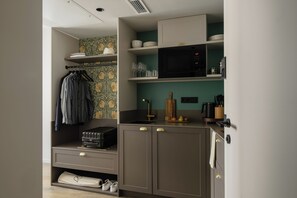 A compact kitchenette with a microwave, shelves with dishes, a sink, and a small countertop. - Bob W Vienna Döbling (Vienna)