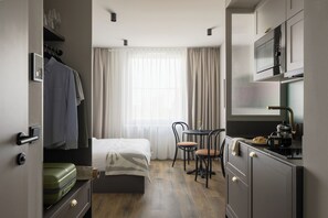A compact hotel room with a bed, a small dining table, chairs, a kitchenette, and a wardrobe. - Bob W Vienna Döbling (Vienna)