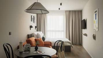 Habitación de hotel con comedor, una cama, televisión y un tablón de anuncios en la pared.