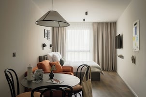Quarto de hotel com área de refeições, cama, televisão e um mural.