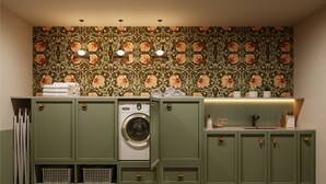 A laundry room with a washing machine, green cabinets, and a patterned wall. - Bob W Vienna Döbling (Vienna)