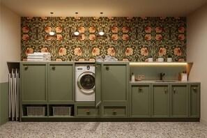 A laundry room with a washing machine, green cabinets, and a patterned wall. - Bob W Vienna Döbling (Vienna)