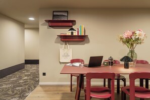 A dining area with a table, chairs, a laptop, a coffee maker, and a vase with flowers. - Bob W Vienna Döbling (Vienna)