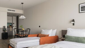 A hotel room with two beds, a dining table, chairs, a small kitchen area, and a framed picture on the wall. - Bob W Vienna Döbling (Vienna)