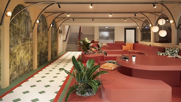 A modern lobby with a curved reception desk, seating areas, and a staircase.