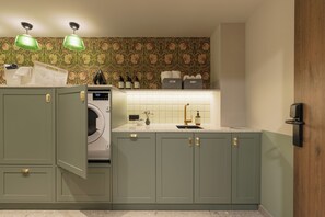A compact kitchen with a washing machine, a sink, and storage cabinets. - Bob W Vienna Döbling (Vienna)