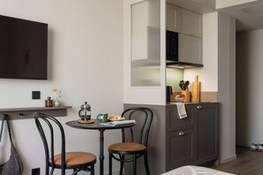 A compact kitchen with a dining area, including a table with chairs, a coffee maker, and a bowl of fruit. - Bob W Vienna Döbling (Vienna)